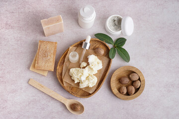 Composition with plate of shea butter, nuts and cosmetic products on light background