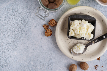 Plate with shea butter and nuts on light background