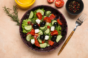 Bowl of tasty Greek salad, fork, oil and spices on color background