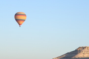 A hot air balloon is floating in the sky above a mountain