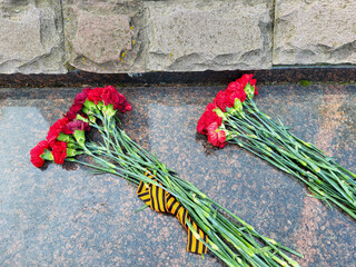 Two bouquets of red carnations lie on a marble slab.