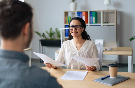Searching for job concept. Happy human resources manager speaking to employment applicant on work interview, holding CV at office. Personnel manager talking to vacancy candidate