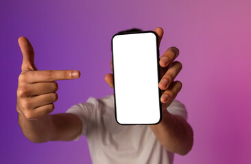 Unrecognizable young man holding smartphone in front of his face, pointing at empty screen,...