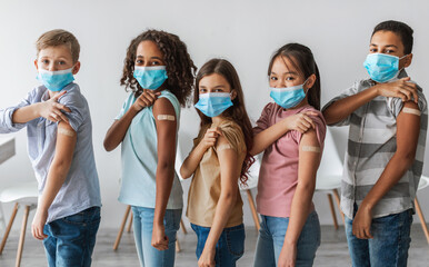 Kids Vaccination Against Covid-19. Diverse Group Of Vaccinated Children Showing Arms With Medical Plaster Bandage After Antiviral Vaccine Injection Standing Over Gray Wall Background