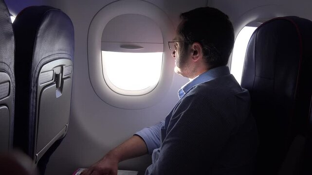 Man looking on airplane window during the flight