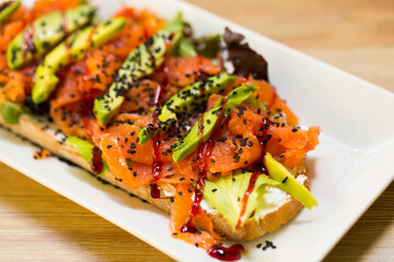 Salmon toast with lettuce, avocado and cheese is tasty dish in the kitchen.