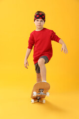 Little boy with skateboard on yellow background