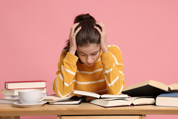 Preparing for exam. Student with books at table against pink background