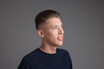 Fototapeta premium Handsome young man with stylish haircut on grey background