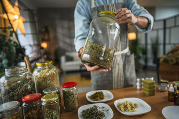 close up of man hands hold big jar in apron in workshop at home