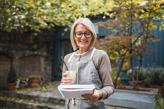 Mature woman waitress read documentation in front restaurant