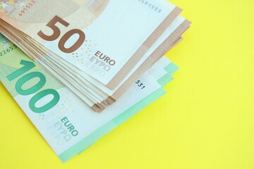 Big amount of one hundred and fifty euro money bills on yellow background