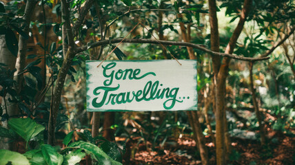 A charming wooden sign hanging from a tree branch, reading 'Gone Travelling...' in green cursive lettering amidst lush foliage.