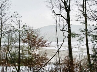 Obraz premium Outdoor winter wonderland in Catskill Mountains. White fresh snow blanket backdrop with frozen water. Gorgeous cold weather scene during November snowstorm. Hike, ski, sled, tube. Enjoy nature!