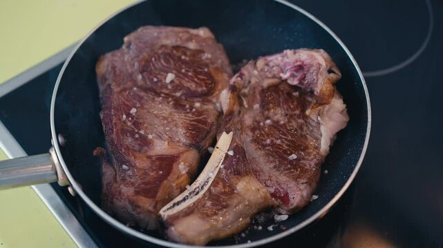Close-up of a dry aged chuleton steak from the Rubia Gallega breed, searing in a hot pan. Known for its marbled texture and buttery aroma, this Spanish delicacy offers a rich, tender experience for