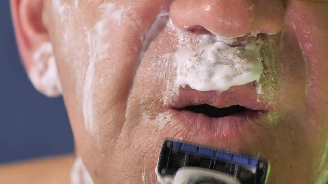 The shaving of the mustache using the razor blade under the mouth.