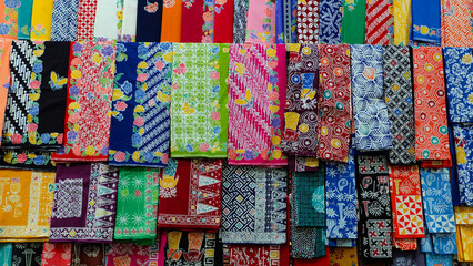 Colorful batik fabrics displayed in a market. Close-up shot highlights intricate patterns and vibrant colors. Perfect for fashion blogs or promoting Indonesian culture