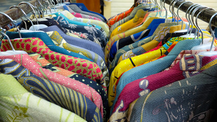 Colorful batik shirts hanging on a rack. Close-up shot highlights intricate patterns and vibrant colors. Perfect for fashion blogs or promoting Indonesian culture