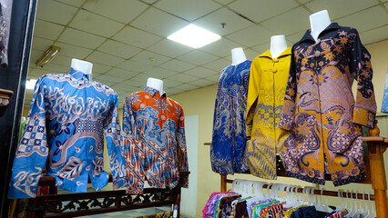 Colorful formal long sleeve batik displayed on mannequins in a shop. wide-angle shot captures the shop's interior. Perfect for fashion blogs or promoting Indonesian culture