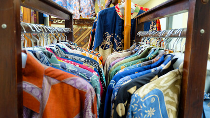 Colorful batik shirts hanging on racks in a shop. Shallow depth of field focuses on the shirts, creating a dreamy atmosphere. Perfect for fashion blogs or promoting Indonesian culture