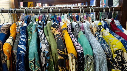 Colorful batik shirts hanging on a rack. Close-up shot highlights intricate patterns and vibrant colors. Perfect for fashion blogs or promoting Indonesian culture