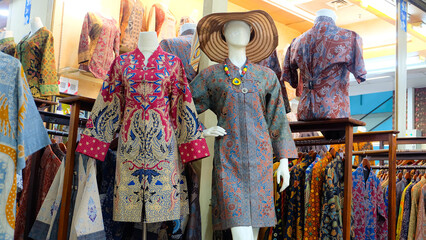 Colorful batik dresses displayed on mannequins in a shop. Selective focus on the dresses, shallow depth of field creates a dreamy atmosphere. Perfect for fashion blogs or promoting Indonesian culture