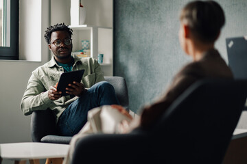 Patient showing information on digital tablet to doctor during therapy session