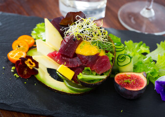 Close up of tasty salad of raw tuna, avocado, mango and greens at plate