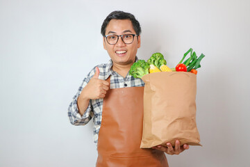 Young man is holding a bag full of vegetables, on white background.