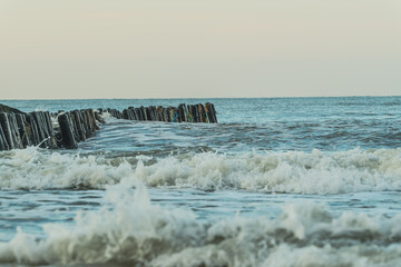 Waves crash against a weathered wooden sea breakwater The structure stands firm against the tides...