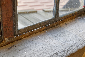 an old vintage retro window made of metal and many small glass panes is not completely airtight, cold and cold air flows through the clearly visible slits between the window and the window frame