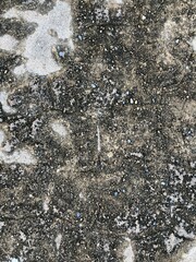 Close-up of an aged asphalt surface with scattered pebbles, dirt, and stains, perfect for textures or urban-themed designs.