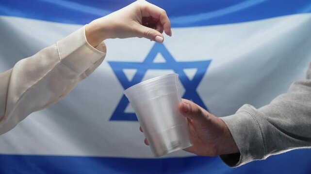 Rich Jewish Woman Throws shekels Coins Into Plastic Cup Of Homeless Man Who Is Asking For alms on Israel flag. Sharing and help each other. Poor life, unemployment, people below poverty line.