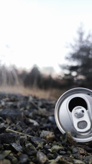 The image shows a discarded can on gravel in the lower right corner, symbolizing leaving trash...