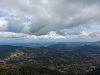 A scenic view of Phu Ruea National Park, Thailand, showcases expansive valleys, lush greenery, and dramatic overcast clouds.