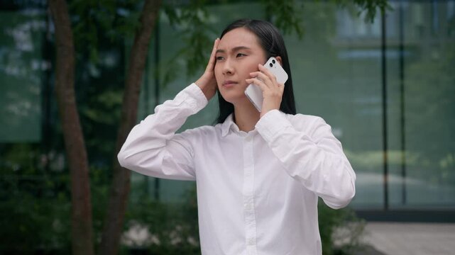 Worried Asian Korean Japanese woman upset girl businesswoman talking mobile phone smartphone business call problem bad news holding head failure headache outdoors student city frustrated female worker
