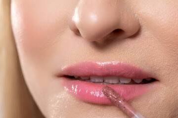 This image features a closeup of glossy lip application with a blurred background