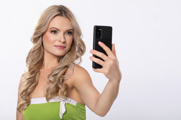 A Young Woman Smiling While Taking a Selfie with Her Smartphone, Dressed in a Bright Outfit