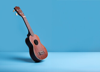 Wooden ukulele guitar on blue background