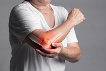 X-ray of elbow,Woman in her 70s holding her elbow with a red pain point. elbow paint and joint pain concept