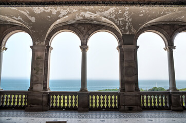 View through the arches from a balcony of a mansion overlooking the ocean. A foggy summer day.