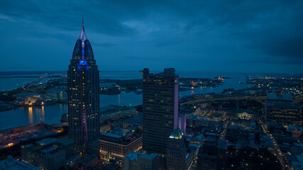 Obraz premium JULY 17, 2023, MOBILE, ALABAMA - USA - aerial view of Mobile Alabama skyline with Mobile Harbor and Port in background at dusk
