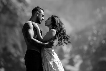 Sensual couple kissing near a waterfall. Passionate couple embracing against summer nature. Romantic lovers at countryside. Fashion portrait of sexy couple in love hugs on amazing landscape.