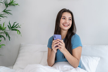 Asian attractive woman using mobile phone chatting at house in morning. 