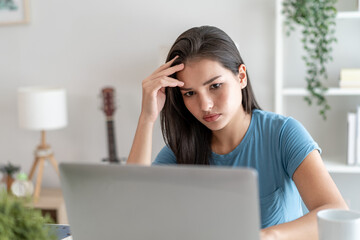 Depressed Asian woman freelancer using laptop device working in house. 