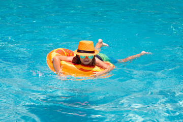 Summer relax. Children swim with floating ring in swimming pool. Kids summer vacation. Happy little boy with inflatable ring in poolside.