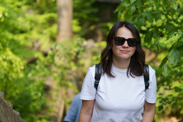 Beautiful smiling dark-haired girl in a white T-shirt and with a backpack on her shoulders in the...