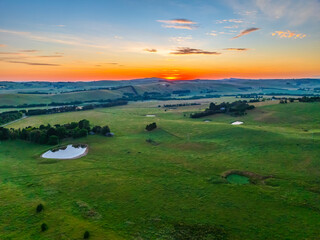 Fototapeta premium Sunrise over the countryside on the outskirts of country town with high cloud