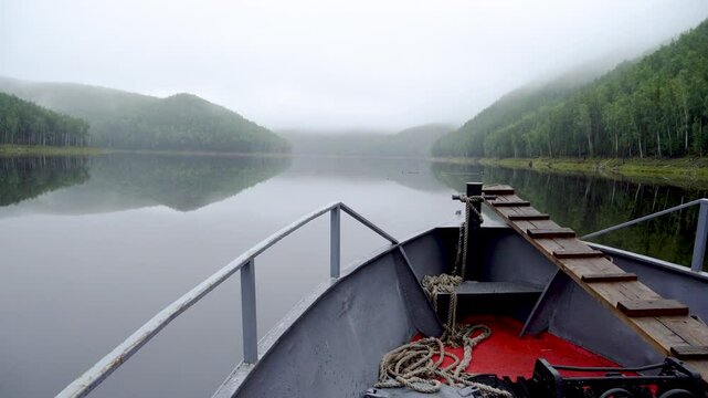 Zeya Reservoir. Picturesque views from a calm lake to green hills and forest. View from a boat. A boat sails along a calm lake.