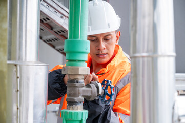 The image captures a skilled engineer inspecting a network of pipelines in a petrochemical facility. the concept of projects related to petrochemicals, engineering, and industrial inspection.